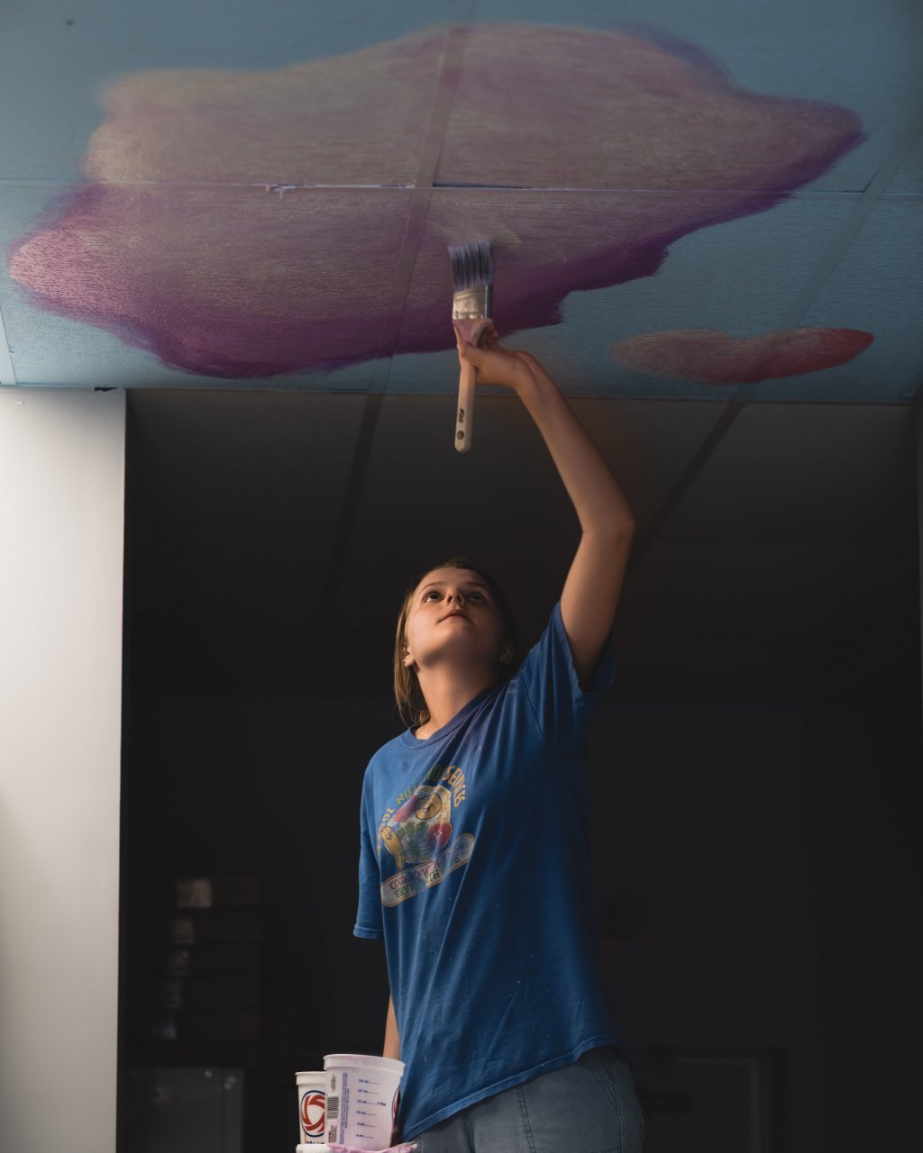 picture of artist hannah painting her pastel cloud ceiling